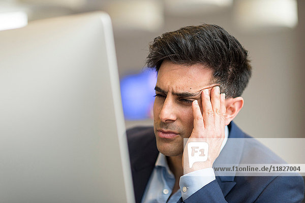 Verwirrter Geschäftsmann betrachtet Computer im Büro