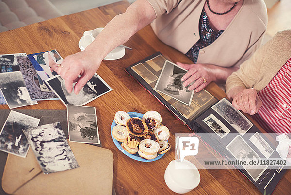 Overhead view of two senior women looking at old photographs at table