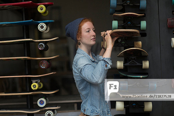 Frau arbeitet im Skateboard-Laden und organisiert Skateboard-Display