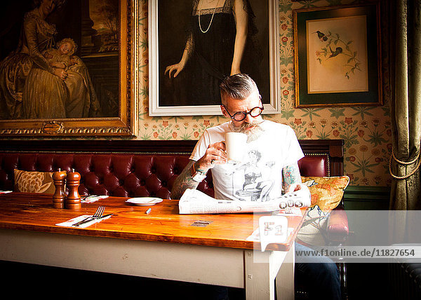 Quirky man reading newspapers in bar and restaurant  Bournemouth  England
