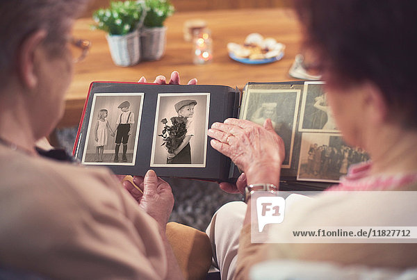 Over shoulder view of two senior women looking at old photograph album
