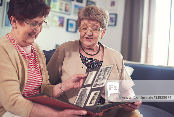 Zwei ältere Frauen auf dem Sofa beim Betrachten eines alten Fotoalbums