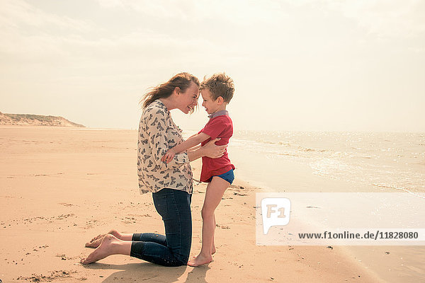 Junge Frau kniend mit Sohn am Strand
