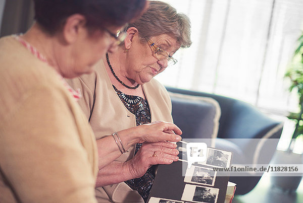 Zwei ältere Frauen auf dem Sofa beim Betrachten eines alten Fotoalbums