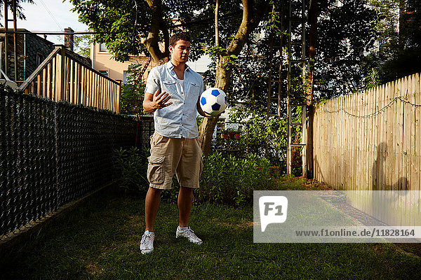 Mann hält Fussball im Garten