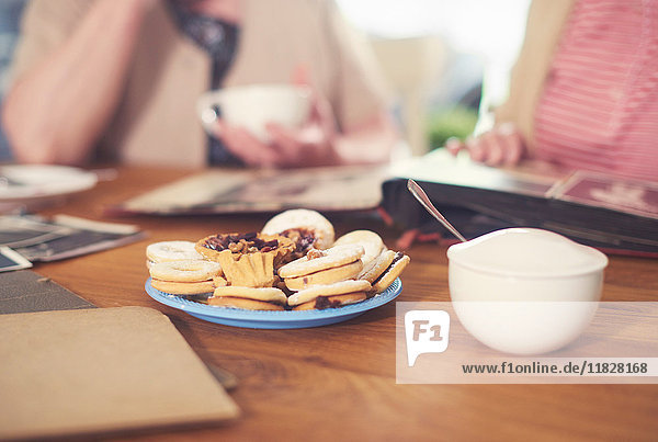 Schnappschuss von älteren Frauen bei Tisch mit Zuckerdose  Keksen und Fotoalbum