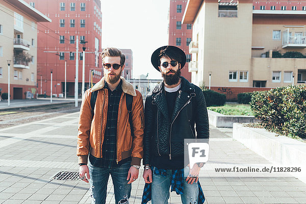 Porträt von zwei jungen männlichen Hipsterfreunden  die in einer städtischen Wohnsiedlung stehen