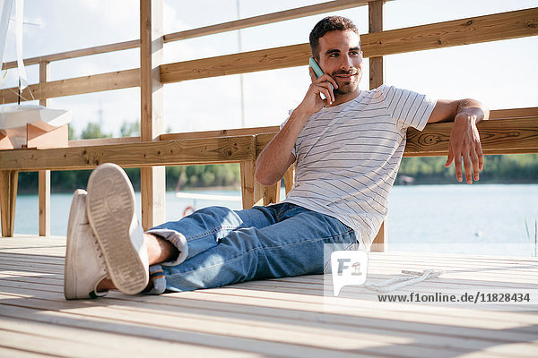 Mann entspannt sich auf dem Pier  spricht über Smartphone