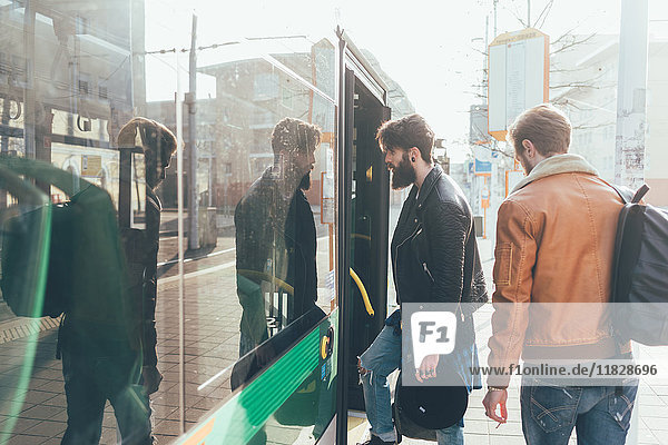 Two young men boarding tram at city tram station
