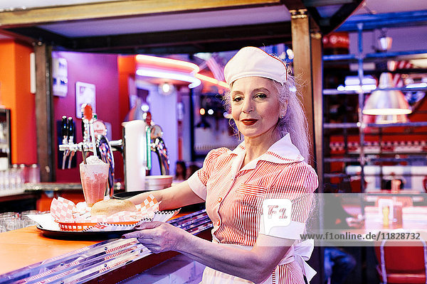 Portrait of mature female waitress in 1950's diner