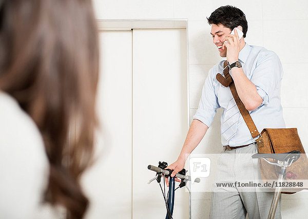 Mann mit Handy im Fahrstuhl mit Fahrrad