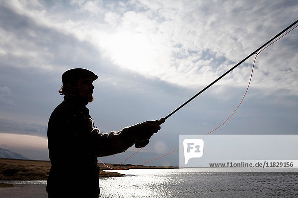 Silhouette eines Mannes  der in einem stillen See fischt