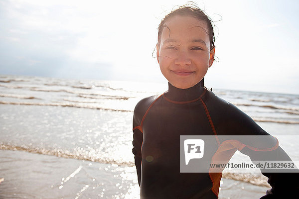 Smiling girl wearing wetsuit on beach