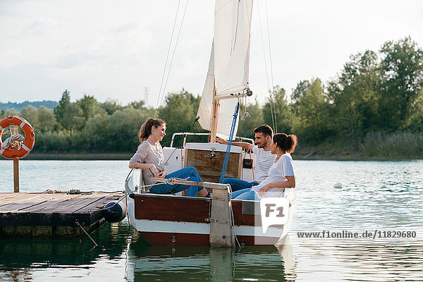 Three friends relaxing on sailing boat on lake