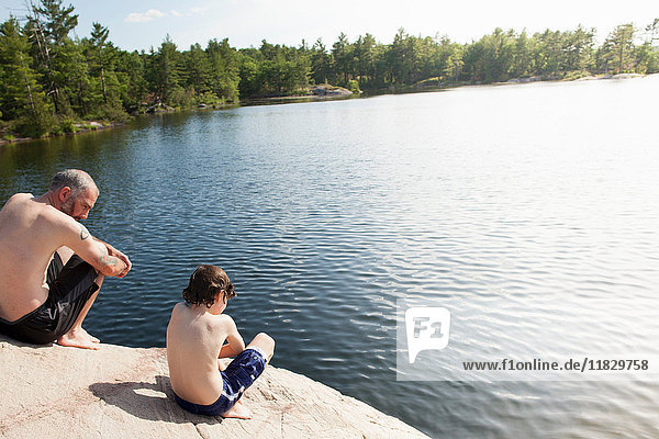 Vater und Sohn sitzen am stillen See
