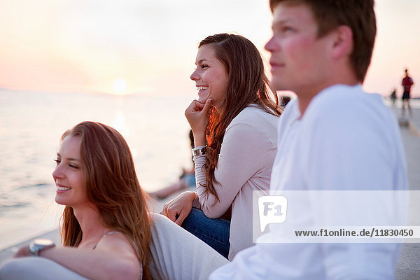 Lächelnde Menschen sitzen auf dem Pier im Freien