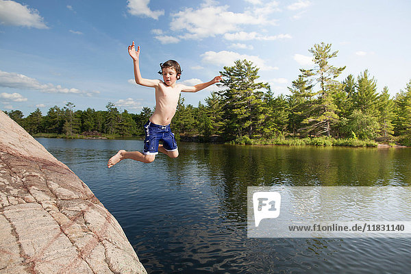 Boy jumping into still lake
