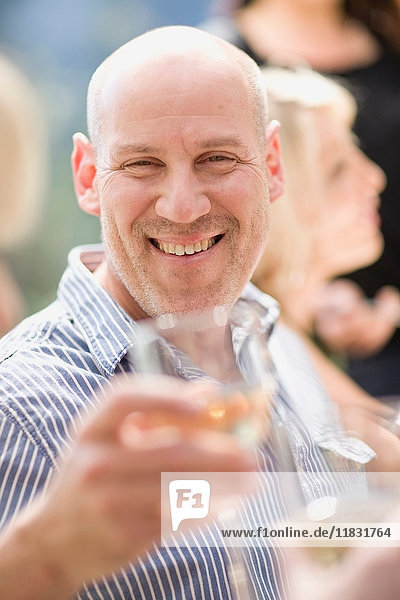 Lächelnder Mann mit einem Glas Wein im Freien