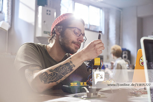 Fokussierter Jungdesigner bei der Montage von Robotern in der Werkstatt