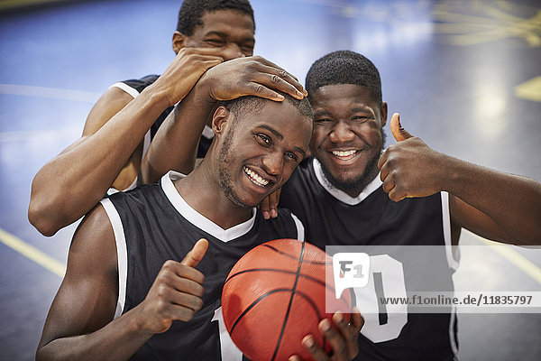 Portrait lächelndes, selbstbewusstes, junges Basketballteam feiert, Daumen hoch gestikulierend