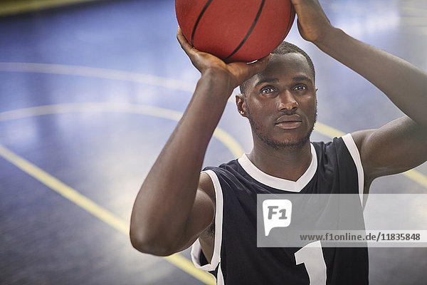 Focused young male basketball player shooting the ball on court