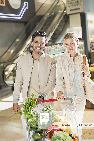 Porträt lächelnd junges Paar mit Einkaufswagen Lebensmittelgeschäft Einkaufen im Markt