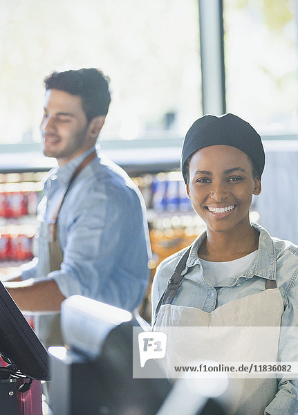 Portrait smiling young female cashier working at grocery store market checkout