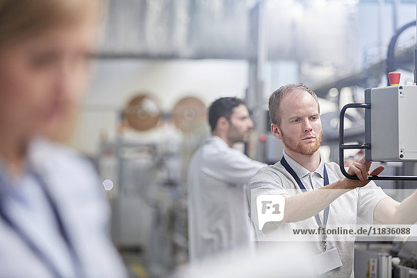 Male worker using machinery control panel in factory