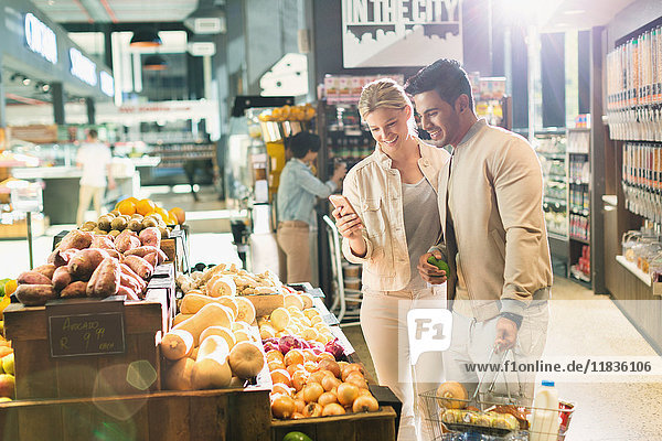 Junges Paar mit Handy beim Einkaufen im Supermarkt