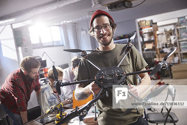 Portrait smiling male designer holding drone in workshop