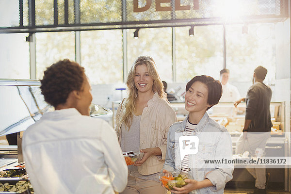 Young women friends at salad bar in grocery store market