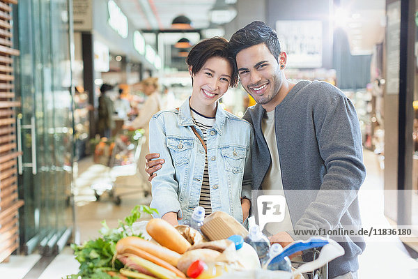 Portrait smiling young couple grocery shopping in market