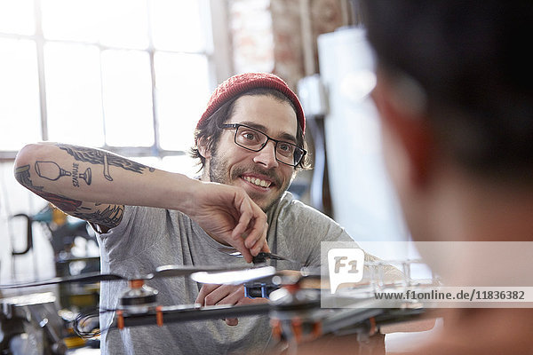 Smiling male designer with tattoos assembling drone