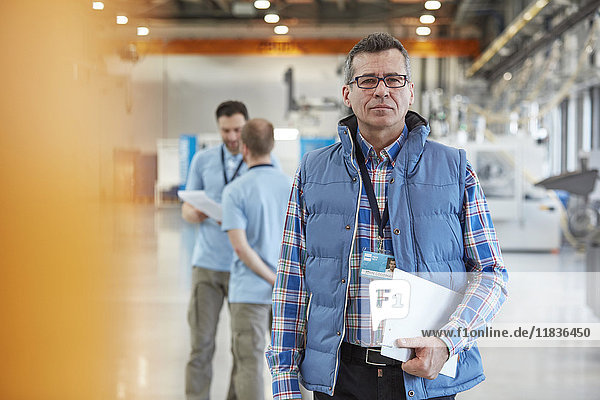 Portrait confident male supervisor with clipboard in factory