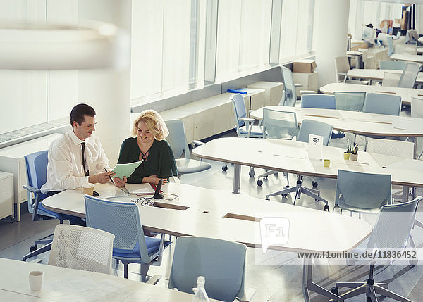 Geschäftsmann und Geschäftsfrau besprechen den Papierkram am Tisch in einem gemeinsamen Arbeitsbereich.