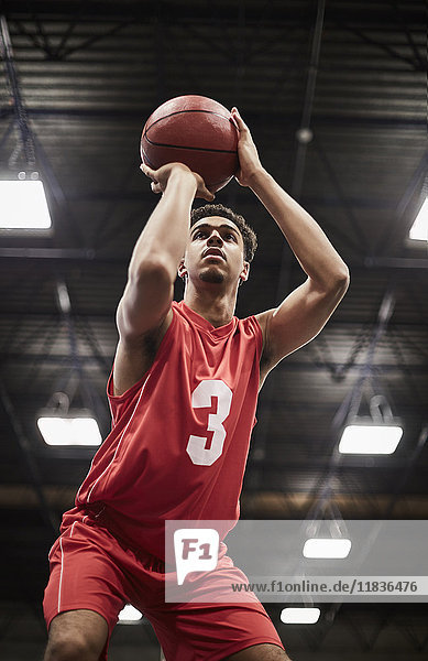 Focused young male basketball player shooting free throw