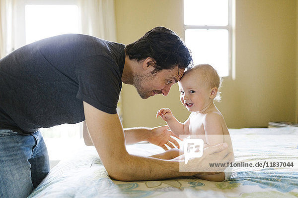 Vater spielt mit einem kleinen Jungen (12-17 Monate) im Schlafzimmer