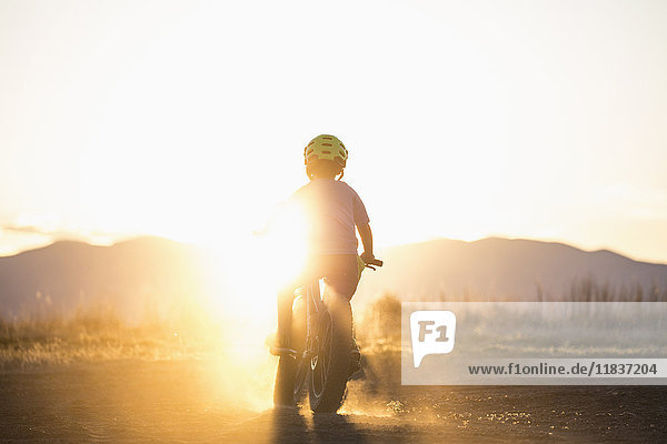 USA  Colorado  Rückansicht eines Jungen (8-9)  der bei Sonnenuntergang Rad fährt