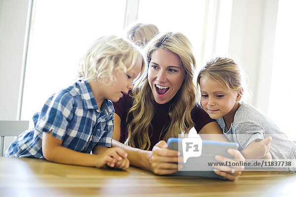 Mutter mit Kindern (4-5  6-7  8-9)  die ein digitales Tablet benutzen