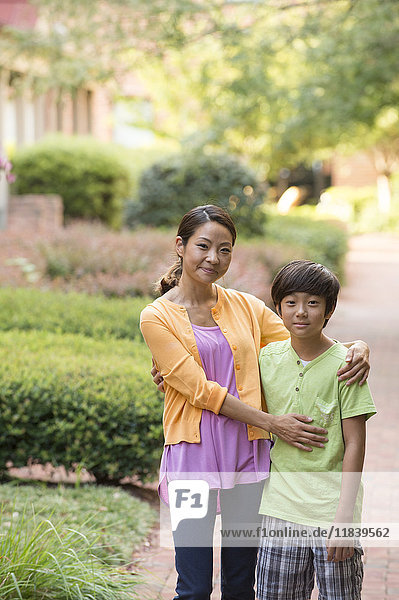 Portrait of Asian mother and son standing on sidewalk