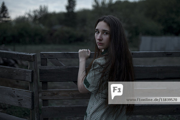 Caucasian woman leaning on wooden gate
