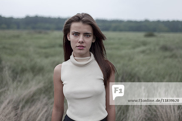 Serious Caucasian teenage girl standing in field