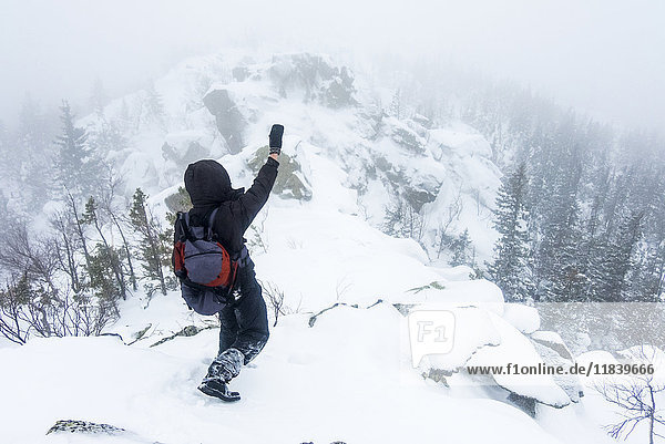 Kaukasischer Wanderer winkt auf verschneitem Berg