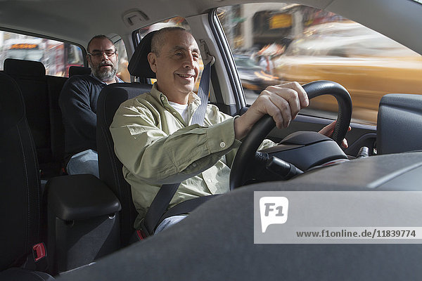 Smiling Hispanic man driving car with passenger
