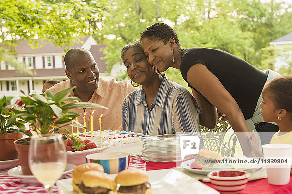 Multi-generation family celebrating with cake at picnic