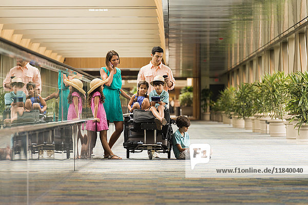 Familie wartet im Flughafen und benutzt Handys