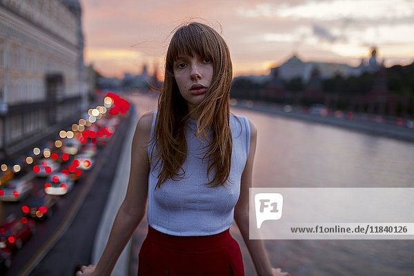 Serious Caucasian woman standing at urban waterfront