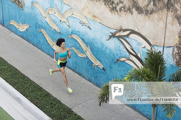Hohe Winkel Ansicht von Mixed Race Frau läuft auf dem Bürgersteig in der Nähe Wandmalerei