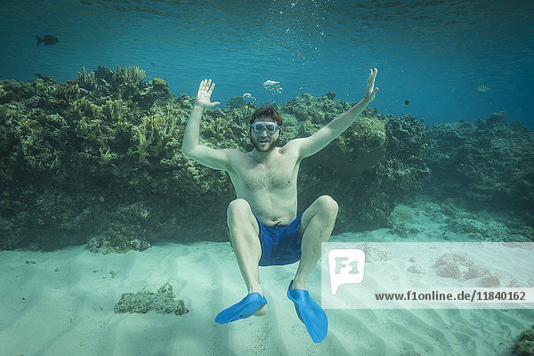 Porträt eines lächelnden Mannes  der unter Wasser im Ozean schwimmt