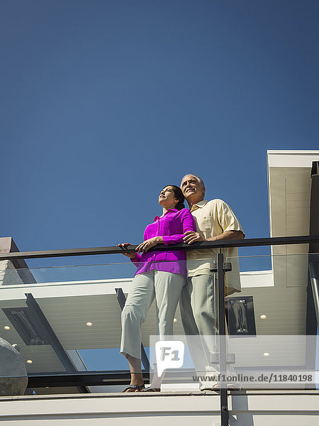 Lächelndes Paar auf modernem Balkon stehend